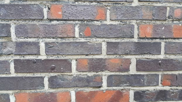 Closeup texture of red brick wall. A background of a weathered old exterior brick wall in the sunshine.