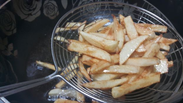 Closeup view of potato french fries or roasted potato sticks in metal gaze with copy space for text