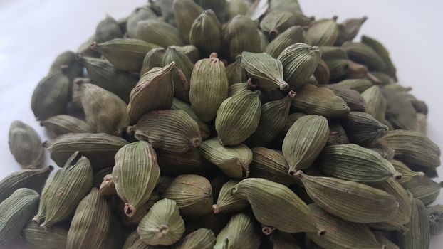 Closeup top view of dried green Elettaria cardamomum fruits with seeds, cardamom spice on white background