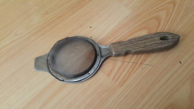 Close up view of chinois with metal gaze place on a wooden floor. This chinois is use for tea infusion in traditional tea services.