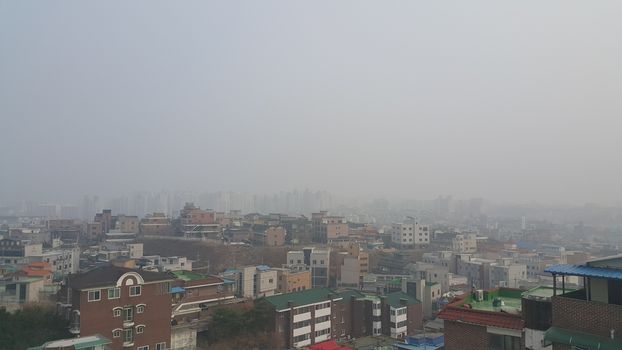 Cityscape aerial view of developed country with  dusty, smogy or amoky background in the sky and skyscraper buildings.