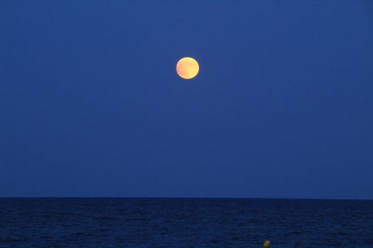 Arenales del Sol Beach in Alicante, Spain, at dusk with a full moon