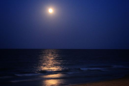 Arenales del Sol Beach in Alicante, Spain, at dusk with a full moon