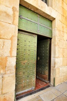 Old and colorful green wooden door with iron details in Alicante, Spain
