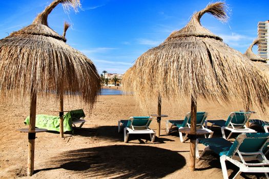 Beautiful Ermita beach in a sunny day in Mazarron, Murcia, Spain. Umbrellas and hammocks in the foreground.