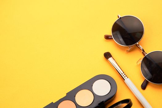 Eyeshadows on a yellow background professional cosmetics makeup brushes soft sponge fashion glasses. High quality photo