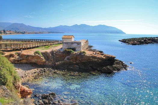 Old thermal baths on the beach with boulders, cliffs and mountains in Isla Plana village in Cartagena, Murcia, Spain in a sunny day