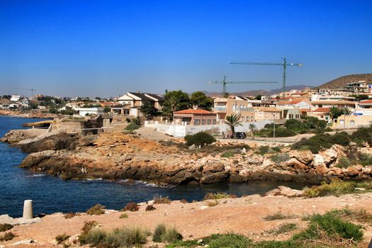 Beautiful beach with boulders, cliffs and mountains in Isla Plana village in Cartagena, Murcia, Spain in a sunny day