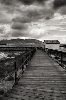 Wooden boardwalk along the beach in a stormy day in Isla Plana village in Cartagena, Murcia, Spain