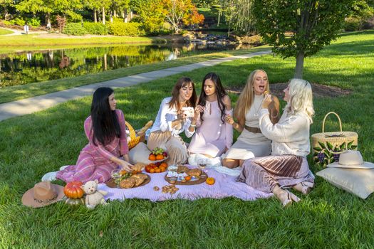 A group of beautiful women enjoy a picnic on a fall day outdoors