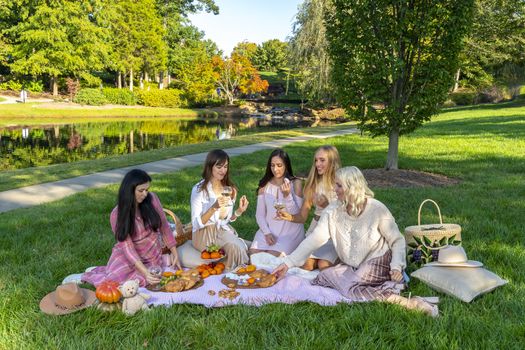 A group of beautiful women enjoy a picnic on a fall day outdoors