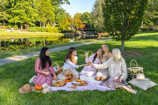 A group of beautiful women enjoy a picnic on a fall day outdoors