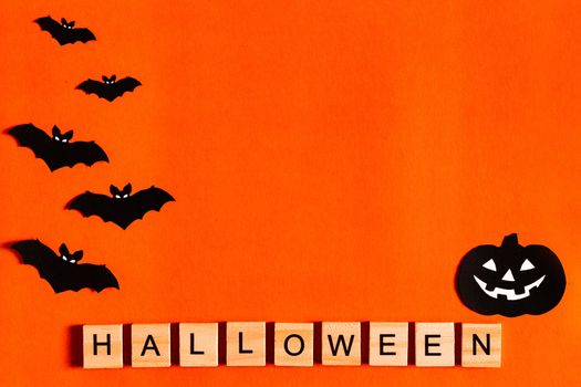 Halloween lettering on orange background with black paper silhouettes, bats, pumpkin, spider. The Concept Of Halloween. the view from the top.
