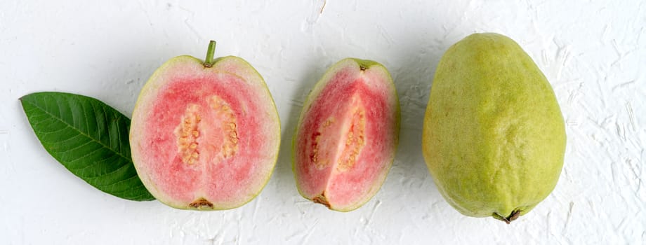 Top view, flat lay of delicious beautiful Red guava with fresh green leaves isolated on white table background, studio overhead table shot with copy space.