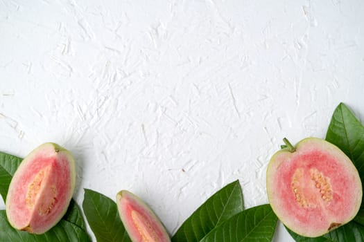 Top view, flat lay of delicious beautiful Red guava with fresh green leaves isolated on white table background, studio overhead table shot with copy space.
