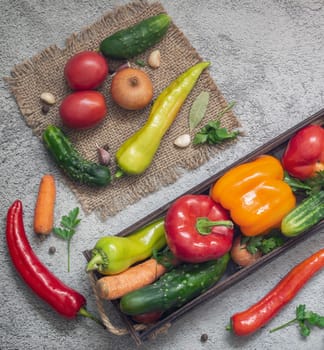 In a wooden container and on a napkin a variety of ripe vegetables: tomatoes, peppers, cucumbers, parsley, zucchini. Top view . Flat lay