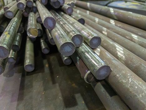 unadorned shot of raw stainless steel rods storage - closeup with selective focus and background blur.