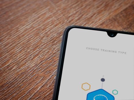 Lod, Israel - July 8, 2020: Elevate - Brain training games app launch screen with logo on the display of a black mobile smartphone on wooden background. Top view flat lay with copy space.