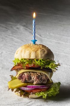 single cheeseburger with a burning candle