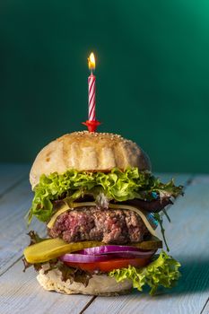 single cheeseburger with a burning candle
