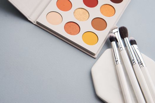 Palette with shadows and professional brushes on a stand on a gray background. High quality photo