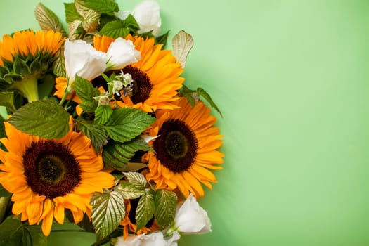 Bright juicy bouquet of sunflowers and white eustomas on a green background. Layout. Flat lay.