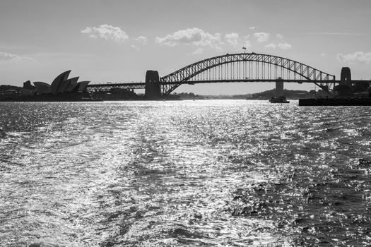 Black and white backlight view of Harbour bridge and the Opera House from the bay in a sunny afternoon