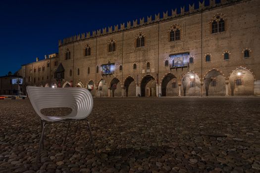 An empty chair in piazza Sordello in the historic Lombard city of Mantua, night photography in Italy