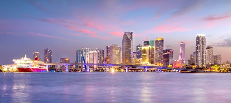 Miami city skyline panorama at twilight with urban skyscrapers and bridge