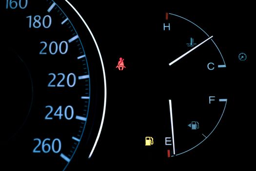 car dashboard shows low fuel warning light, selective focus