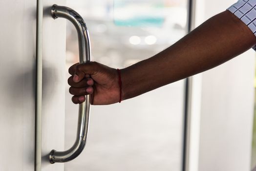 Close up of young hand black man holding and pulling open the door at day time 