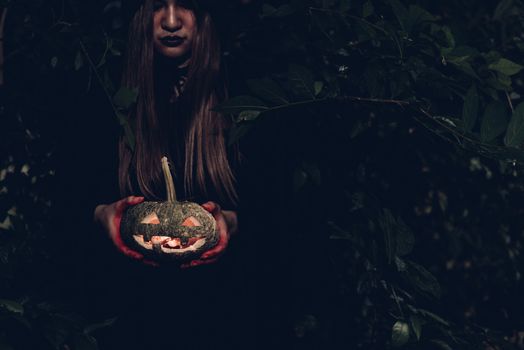 Portrait of woman ghost horror her have pumpkin on hand in forest, halloween day concept