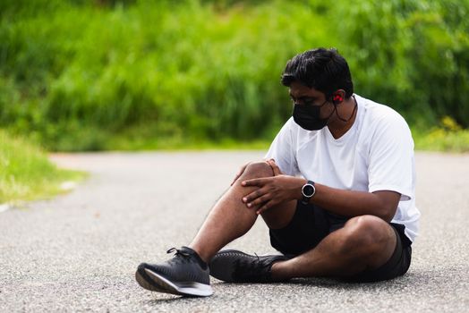 Close up Asian sport runner black man wear watch sitting he uses hands joint hold on his knee while running at the outdoor street health park, healthy exercise Injury from workout concept