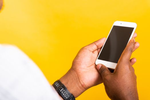 Closeup Asian happy portrait young black man holding digital mobile smartphone blank screen space on hands, studio isolated on yellow background