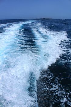 Wake in the sea left by a boat and Tabarca Island in the background. Alicante, Spain.