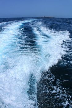 Wake in the sea left by a boat and Tabarca Island in the background. Alicante, Spain.