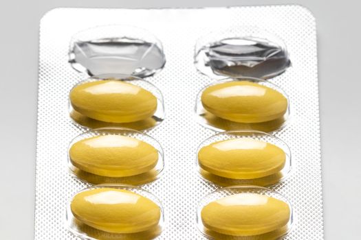 yellow pills in blister pack, medicines for health, pharmaceutical health care and sciences concept, shallow depth of field