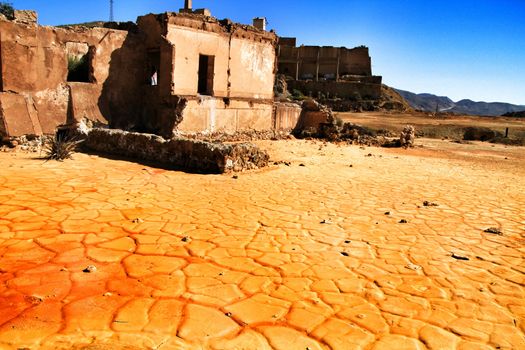 Colorful orange sediments deposited in a dry lake of an old abandoned mine in Mazarron, Spain. Old abandoned house in the background.