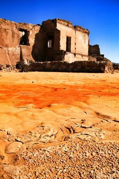 Colorful orange sediments deposited in a dry lake of an old abandoned mine in Mazarron, Spain. Old abandoned house in the background.