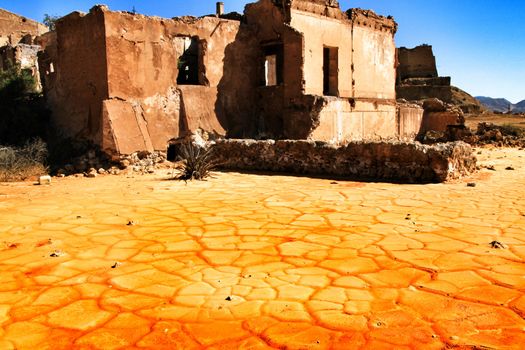 Colorful orange sediments deposited in a dry lake of an old abandoned mine in Mazarron, Spain. Old abandoned house in the background.