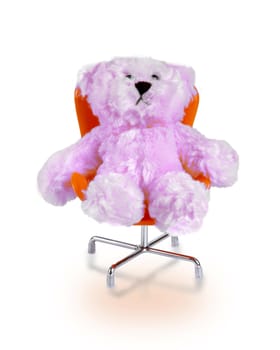 Little pink bear doll sitting in orange chair on white background.