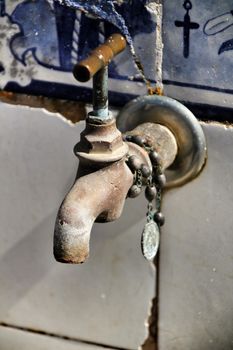 Old tap with rosary beads in blessed fountain in Azenhas do Mar