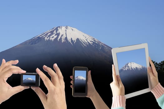 Many people lift hands up to take photo of Mount Fuji by smart device.