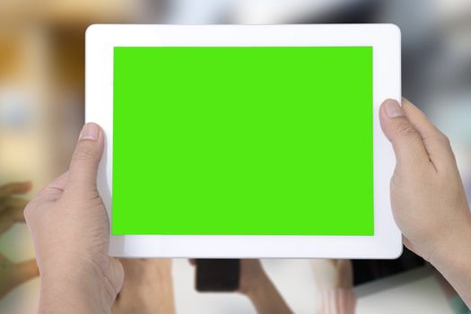 Someone holding digital tablet that show green screen to taking photo while many hands take photo in foreground.