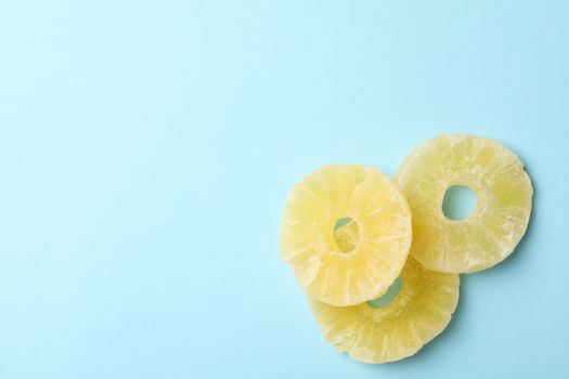 Tasty dried pineapple slices on blue background