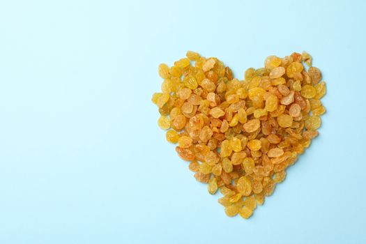 Heart made of raisins on blue background