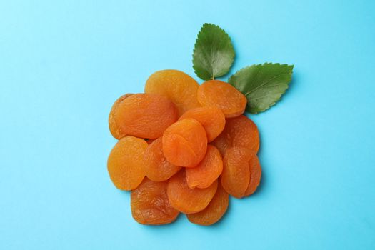 Tasty dried apricot and leaves on blue background