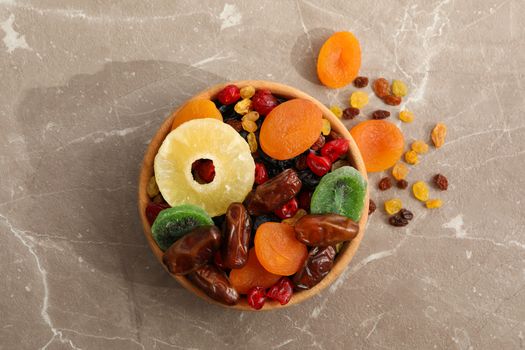 Wooden bowl with dried fruits on gray background