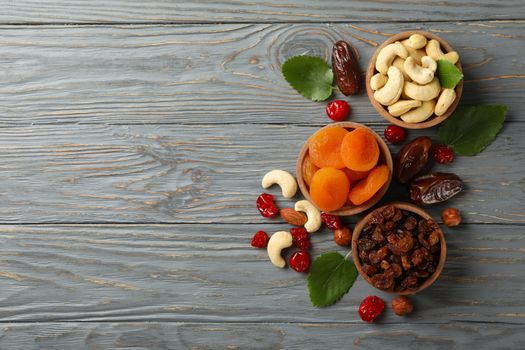 Bowls with dried fruits and nuts on gray wooden background