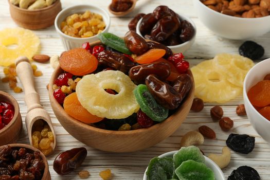 Bowls with dried fruits and nuts on white wooden background